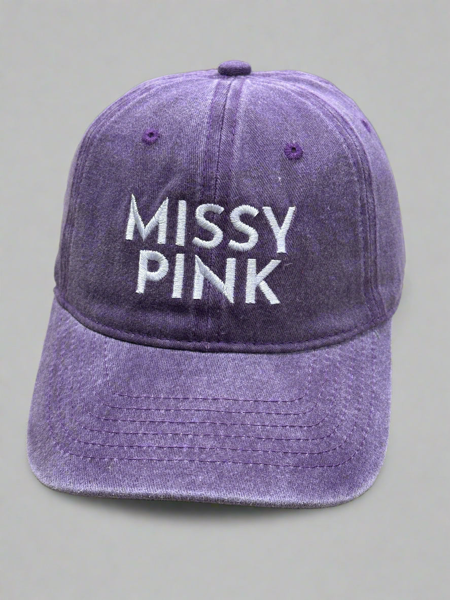 Purple cap with 'MISSY PINK' text on a beige surface