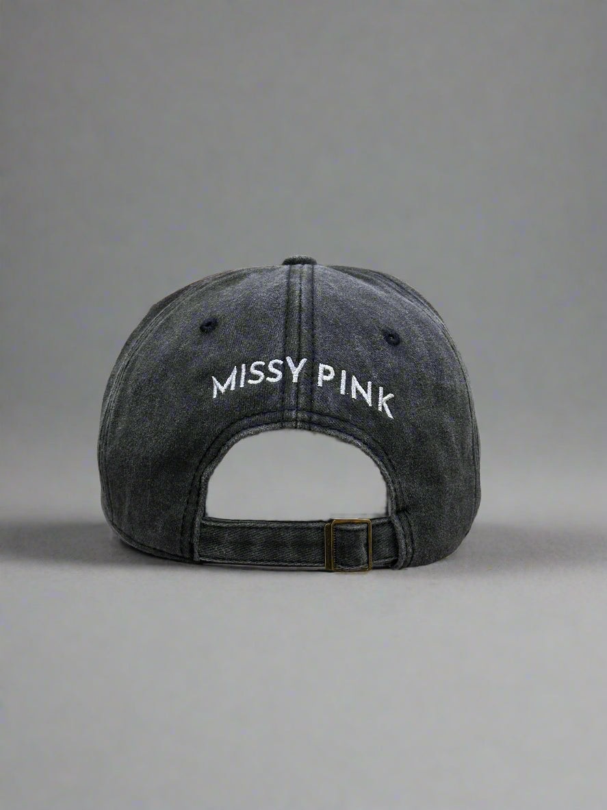 Black cap with 'MISSY PINK' logo on a gray background