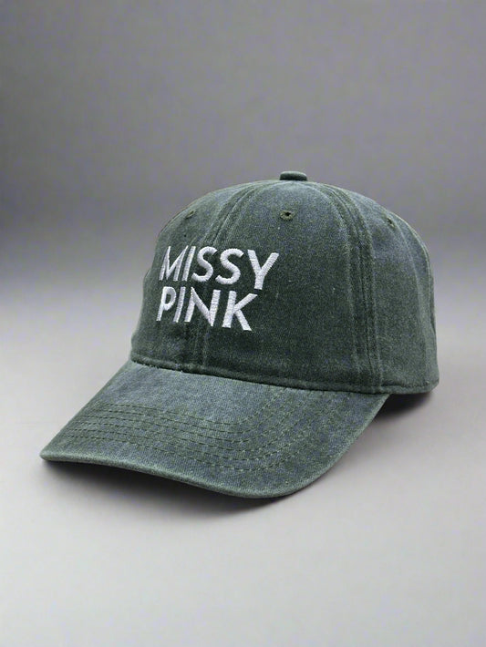 Green cap with 'MISSY PINK' text on a car seat